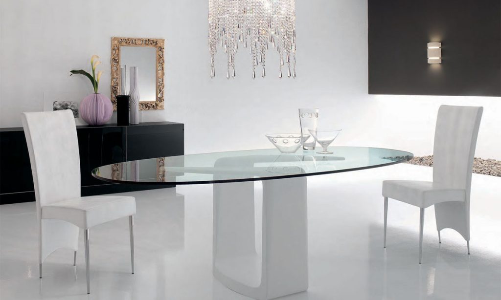 Mesa em formato oval com tampo feito de vidro laminado.