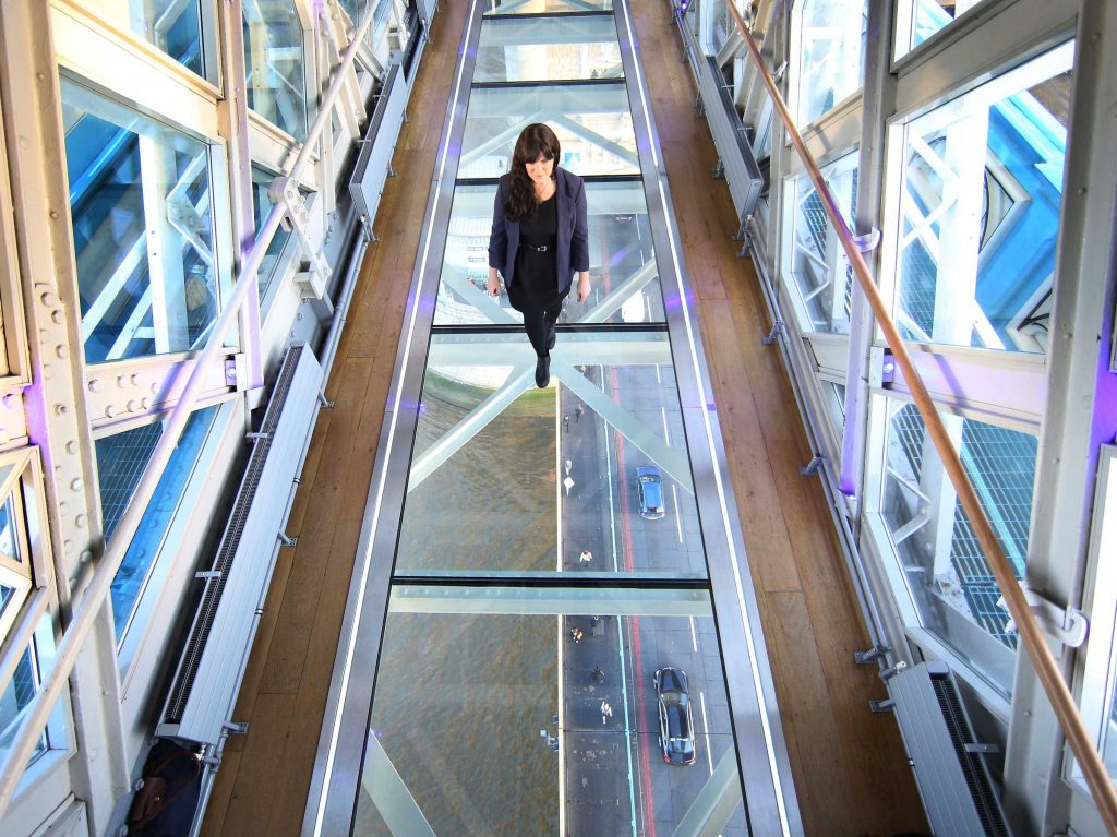 Mulher caminhando sobre piso de vidro laminado.